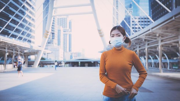 Young woman wearing protective face mask outdoors in city street. New Normal life after COVID-19 and health protocols to avoid infections and the virus spread in public spaces. Thailand