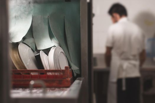 Man washing dish on sink at restaurant