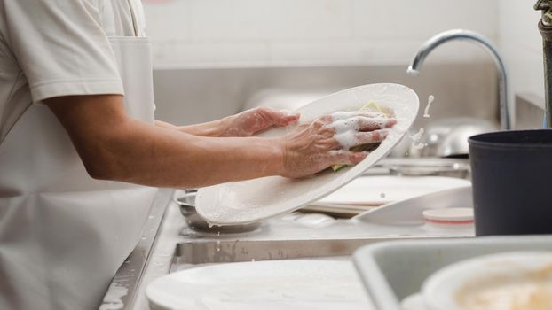 Man washing dish on sink at restaurant