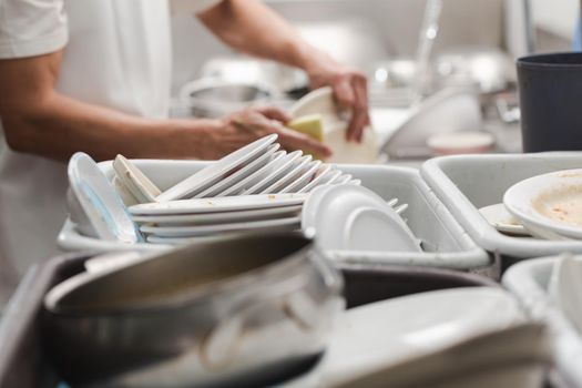 Man washing dish on sink at restaurant