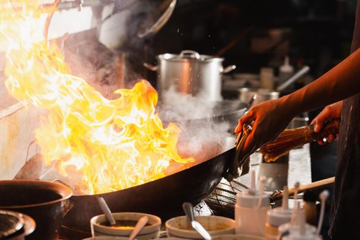 Chef stir fry busy cooking in kitchen. Chef stir fry the food in a frying pan, smoke and splatter the sauce in the kitchen.