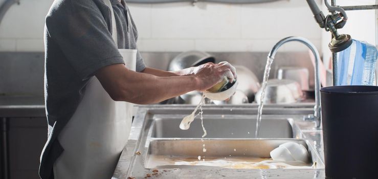 Man washing dish in sink at restaurant.People are washing the dishes too Cleaning solution