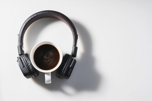 Headphones and coffee cup on white background. Music concept. Top view with copy space