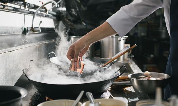 Chef stir fry busy cooking in kitchen. Chef stir fry the food in a frying pan, smoke and splatter the sauce in the kitchen.