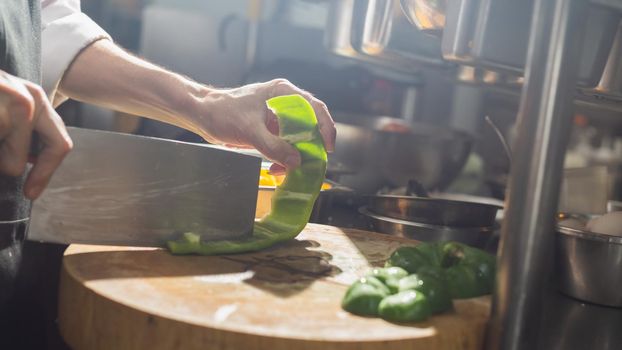 Chef chopping Bell chili with knife in kitchen