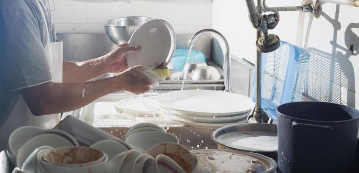 Man washing dish in sink at restaurant.People are washing the dishes too Cleaning solution