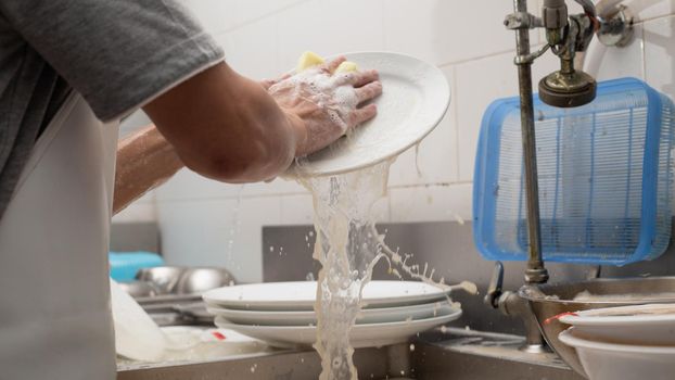 Man washing dish in sink at restaurant.People are washing the dishes too Cleaning solution