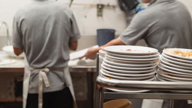 Man washing dish in sink at restaurant.People are washing the dishes too Cleaning solution