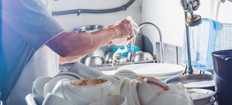 Man washing dish in sink at restaurant.People are washing the dishes too Cleaning solution