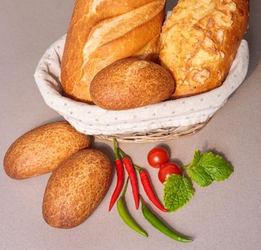 Fresh bread in a basket on the table with red peppers and tomatoes. Close-up