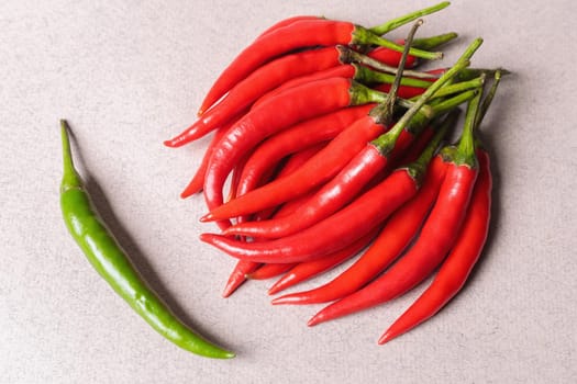 Slide of red chili peppers with one green on a light background. View from above.