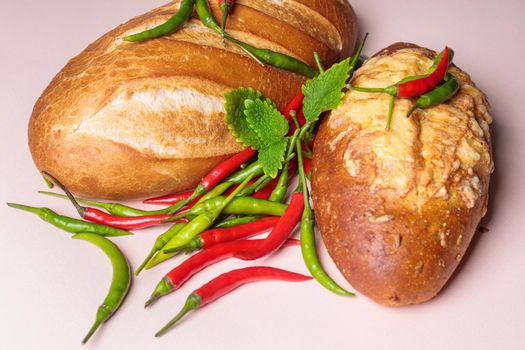 Fresh bread on the table with red and green chili peppers. Close-up