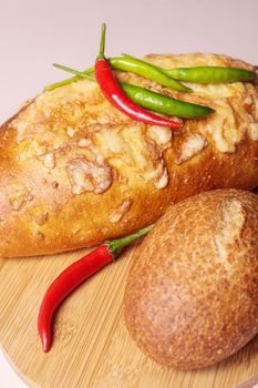 Fresh bread on the table with red and green chili peppers. Close-up