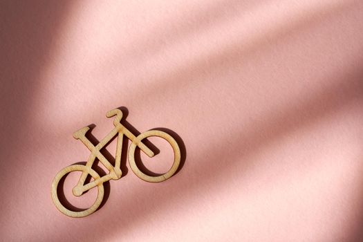 Wooden bicycle going uphill on pink paper background with copy space - transportation concept