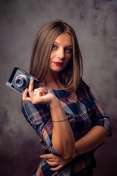Portrait of a beautiful girl with a camera in her hands, half-length studio portrait on a gray background