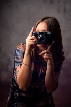 Girl photographer takes pictures with a retro camera, half-length studio portrait on a gray background