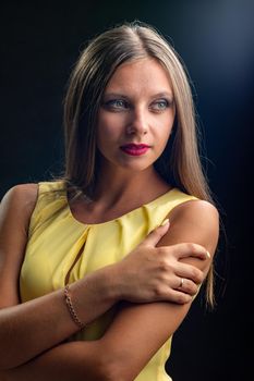 Portrait of a beautiful girl in a yellow dress on a black background