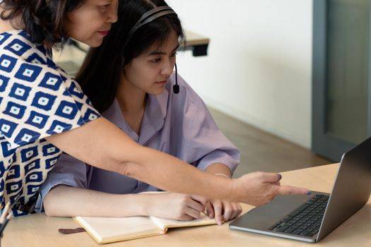 Asian mother with computer notebook teaching daughter to learn or study online at home, Homeschooling online concept