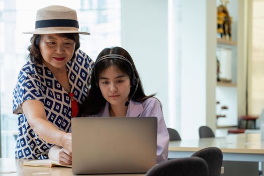 Asian mother with computer notebook teaching daughter to learn or study online at home, Homeschooling online concept