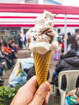 Vanilla ice cream with chocolate and caramel sparks, on street market blur background