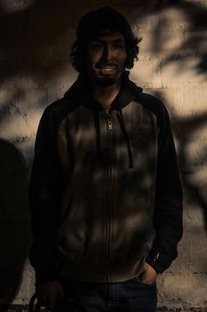 Portrait of young man with beard wearing shirt and shades of trees in the park