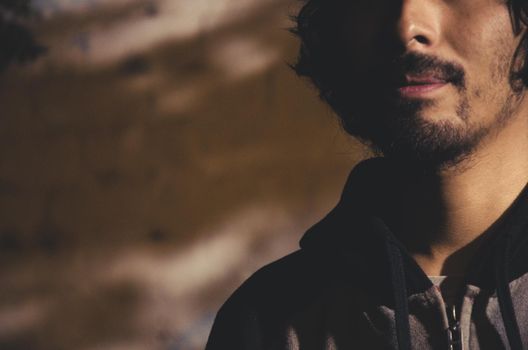 Portrait of young man with beard wearing shirt and shades of trees in the park