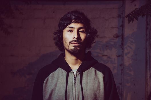 Portrait of young man with beard wearing shirt and shades of trees in the park