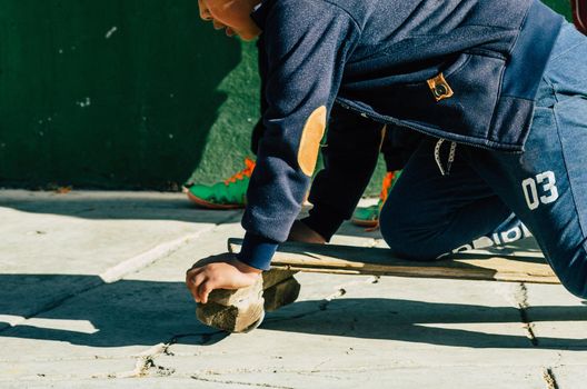 Child playing on the street with an artisan skateboard on a sunny day