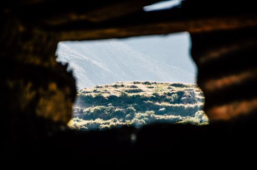 View of a mountain through an old window of an old hut