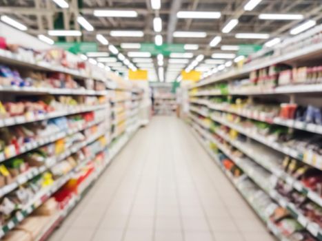 Blurred supermarket aisle with colorful shelves of merchandise. Perspective view of abstract supermarket aisle with copy space in center, can use as background or retail concept