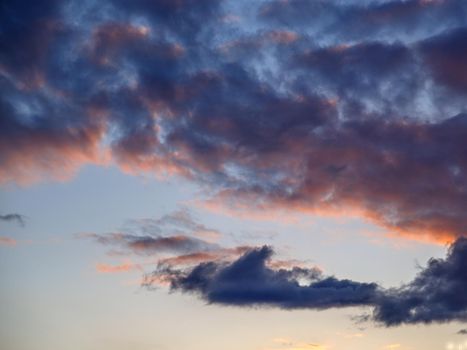 Dark clouds are illuminated by setting sun in spring sky.