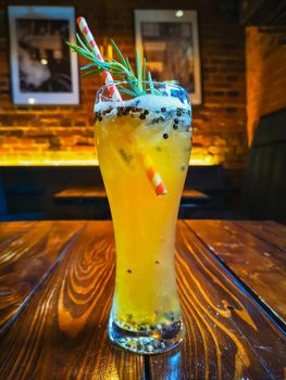 Beer-based drink with rosemary peppercorn and red and white drinking straw