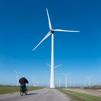 wind turbines under blue sky on philipsdam in dutch province of Zeeland in the netherlands in the netherlands with bicycle