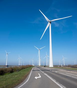 wind turbines under blue sky on philipsdam in dutch province of Zeeland in the netherlands in the netherlands with car