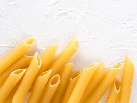 Raw pasta as food background. Italian Penne Rigate Macaroni Pasta on textured white background. Dried pasta selection close up. Top view or flat lay with copy space