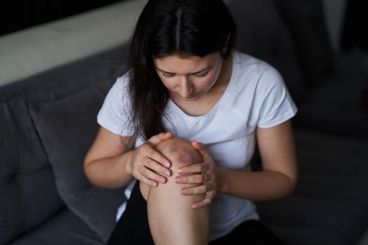 Close-up of a person massaging an injured knee joint. Bruise on the knee. Leg pain.