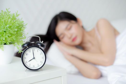 beautiful young asian woman sleep with relax on the bed with alarm clock in the morning, girl sleep with cozy and comfort after tired in the bedchamber, oversleep with time late, lifestyle concept.