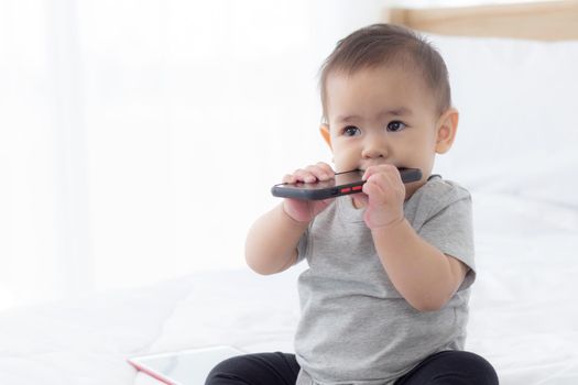Portrait of cute little baby girl sitting with cozy on bed at bedroom, happiness of toddler, newborn 6-11 months with innocence and expression with cheerful, child charm, indoors, one person.