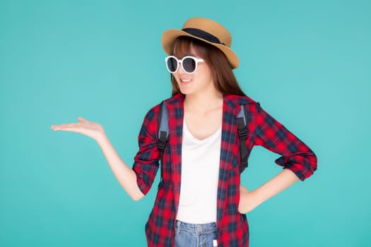 Beautiful portrait young asian woman wear sunglasses and hat smile and enjoy in summer gesture presenting something isolated on blue background, tourist girl in vacation travel concept.