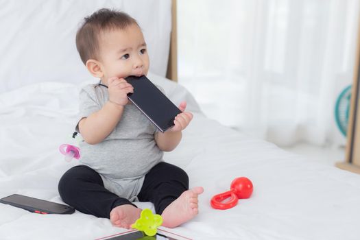 Portrait of cute little baby girl sitting with cozy on bed at bedroom, happiness of toddler, newborn 6-11 months with innocence and expression with cheerful, child charm, indoors, one person.
