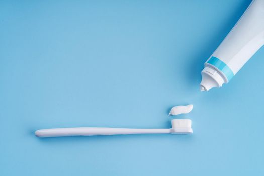 Fashionable toothbrush with soft bristles. Popular toothbrushes. Hygiene trends. Top view with a tube of toothpaste applying on brush.