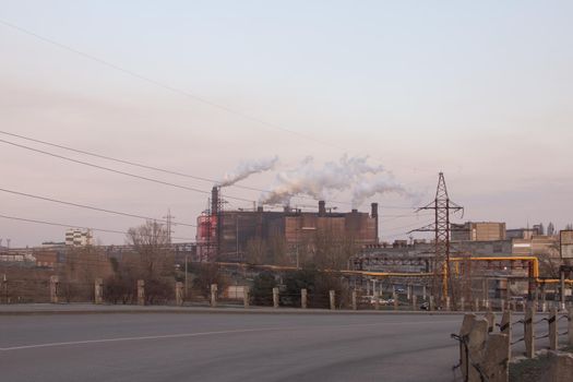 The road leading to the mining plant. You can see a huge industrial complex, smoking pipes, power lines, pipelines.