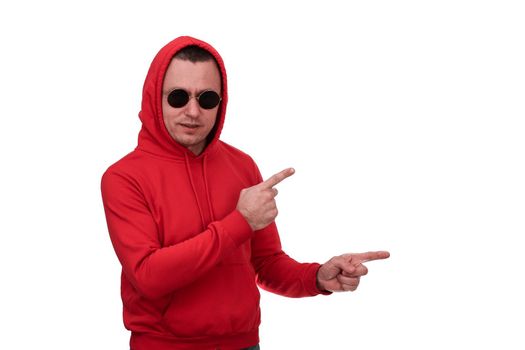 A man in a red hooded sweatshirt and black glasses points to an empty space. Isolated on a white background.