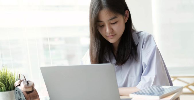Asian beautiful female student study in home with laptop
