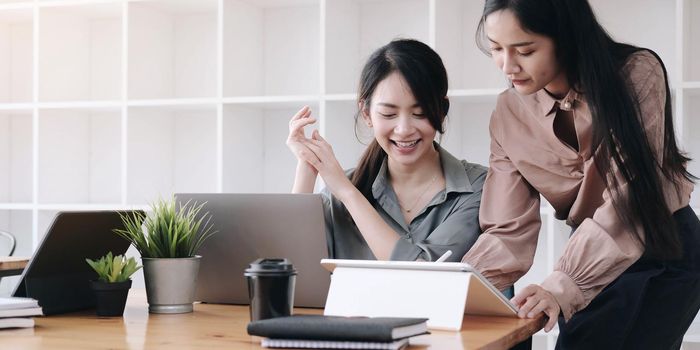 Two young woman designer in casual wear working with laptop and discussing new project at modern office.
