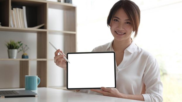 Close up view of female worker showing mock up tablet screen while standing in office room.