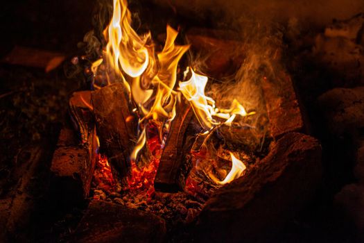 A campfire burns in the snow at night in the snow in the cold winter. The flame of the fire warms and illuminates. Flame, background