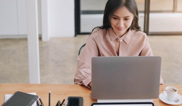 young woman pondering ideas, sitting at desk with laptop, distracted from work, beautiful female looking in distance, taking break.
