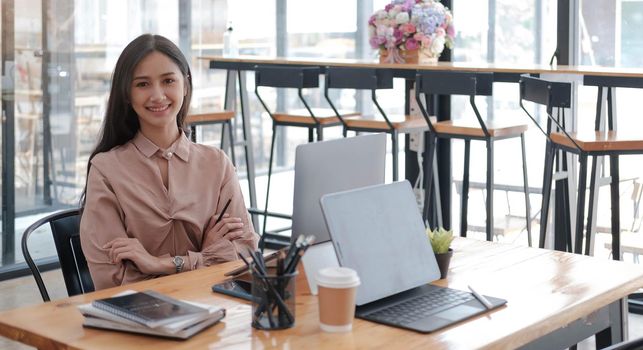 Portrait of smiling businesswoman sitting at desk in the office working on laptop
