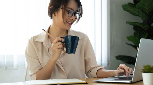 Concept of having a workplace at home. Side profile half-faced photo of happy cheerful smiling excited woman drinking coffee and typing a letter on computer
